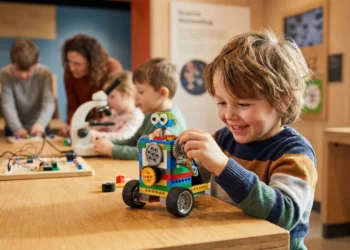 Un enfant souriant assemble des briques colorées lors d'un atelier créatif en Bretagne pendant les vacances d'hiver.