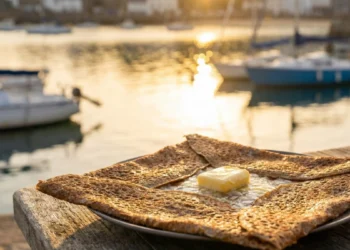 Galette bretonne croustillante au beurre salé posée sur une table face au port de Perros-Guirec au coucher du soleil.