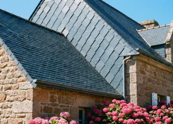 Gros plan sur une toiture en ardoises bleutées traditionnelles sur une maison en granit rose typique de Bretagne.