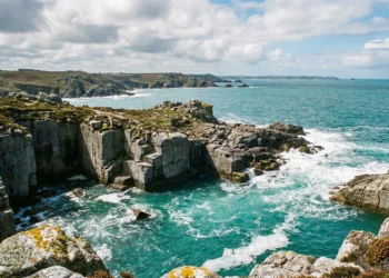 Vue panoramique sur les anciennes carrières de granit de l'Île-Grande à marée haute, avec des vagues s'écrasant sur la roche taillée.