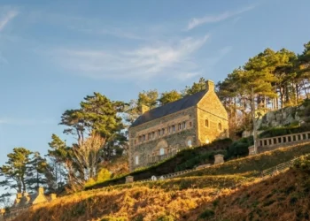 Façade en granit d'une villa Belle Époque surplombant la plage de Trestrignel à Perros-Guirec sous une lumière dorée.