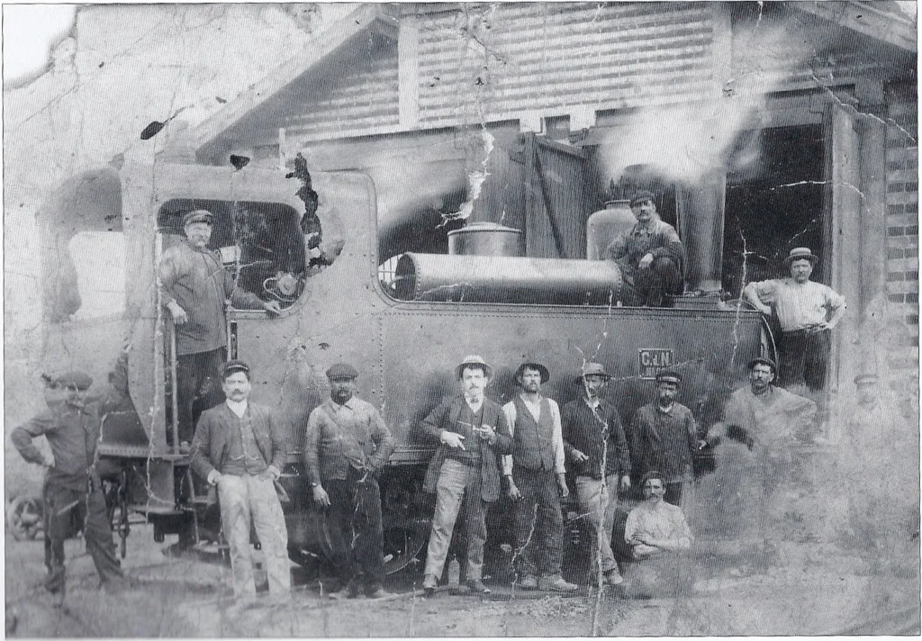 Remise à machines et voitures de Sainte-Catherine aujourd'hui brasserie Philomenn (Tréguier), Première construction en aval pont Canada, l’équipe de mécaniciens devant une locomotive Corpet-Louvet © Collection particulière